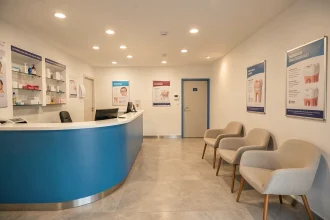 Salle d'attente moderne d'un cabinet dentaire dans la Loire avec un bureau d'accueil épuré et une atmosphère professionnelle